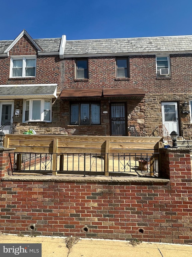 back of house featuring brick siding, a high end roof, and mansard roof