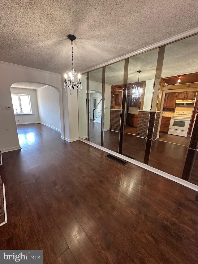 unfurnished dining area with an inviting chandelier, visible vents, arched walkways, and wood-type flooring