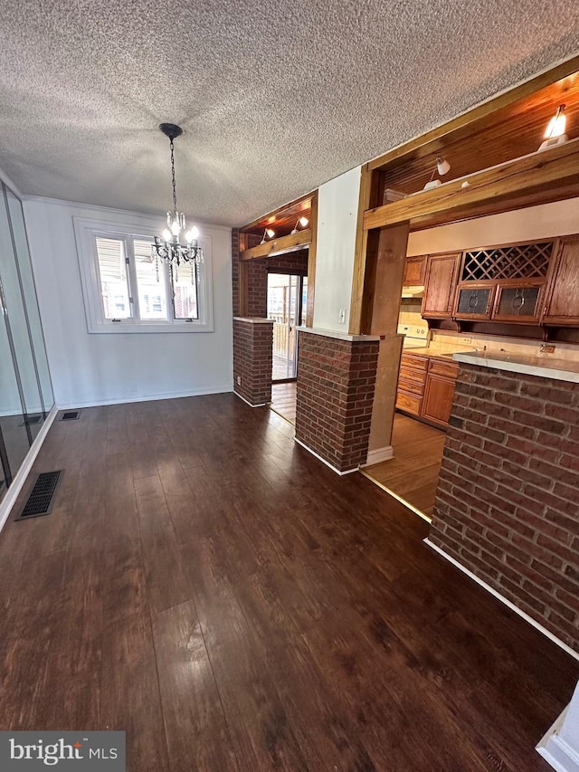 unfurnished dining area with an inviting chandelier, visible vents, dark wood-style flooring, and a textured ceiling