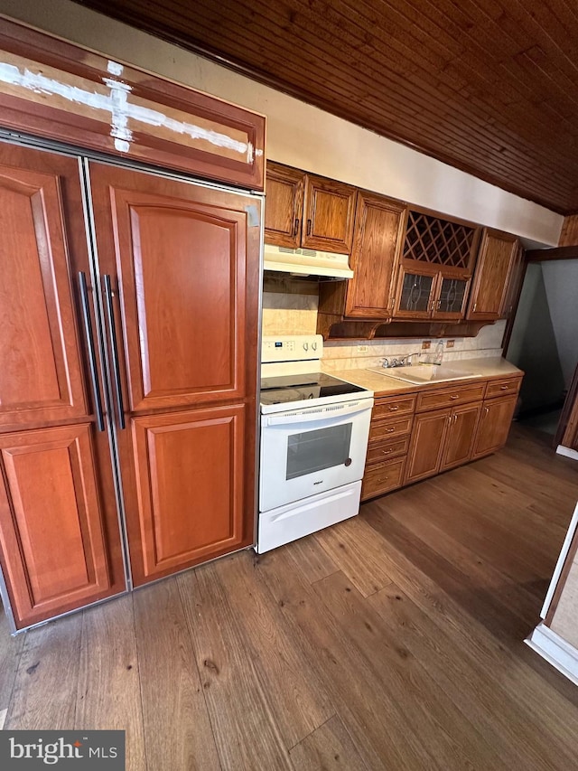 kitchen featuring brown cabinets, dark wood-type flooring, under cabinet range hood, a sink, and white range with electric stovetop