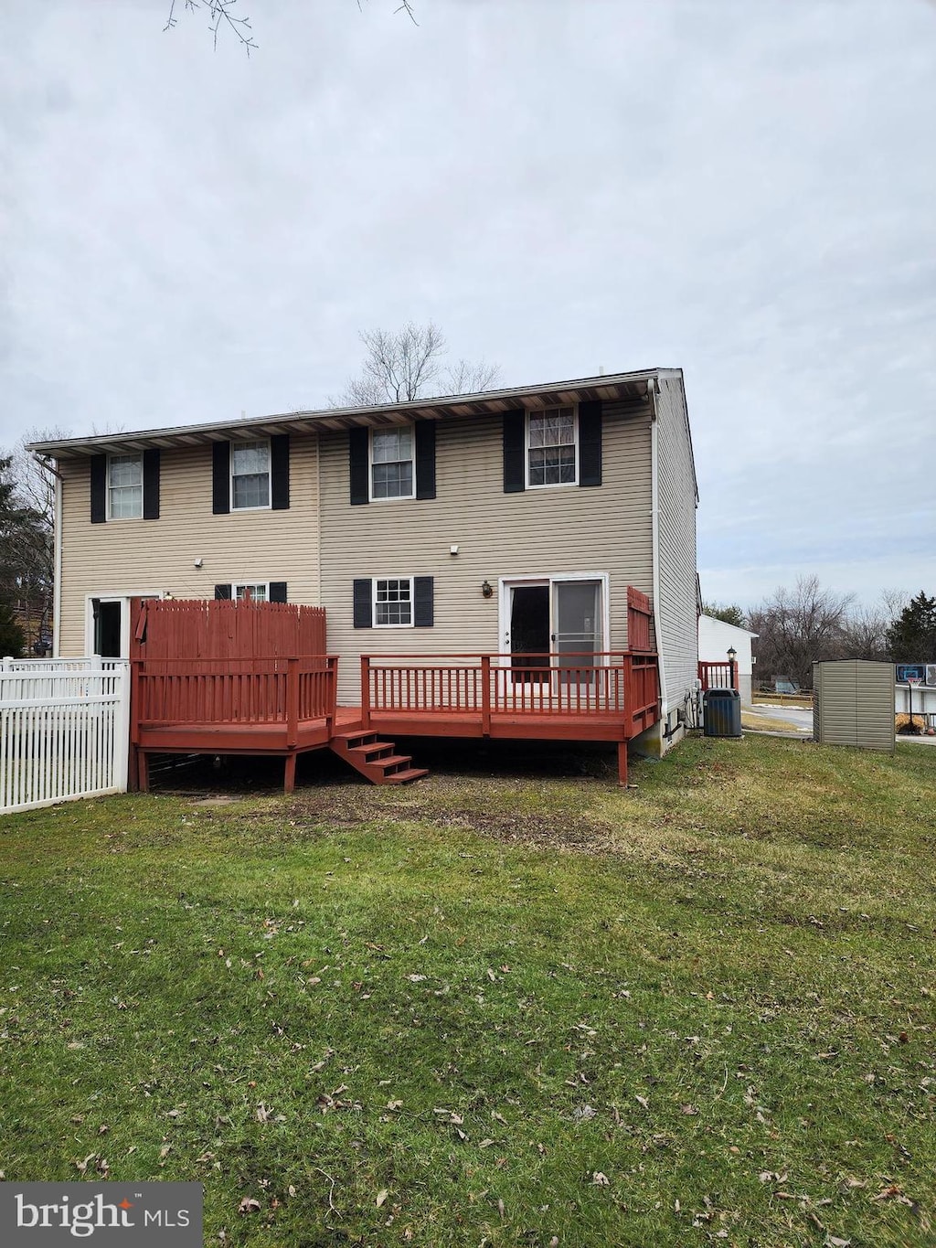 back of property with cooling unit, a lawn, fence, and a wooden deck