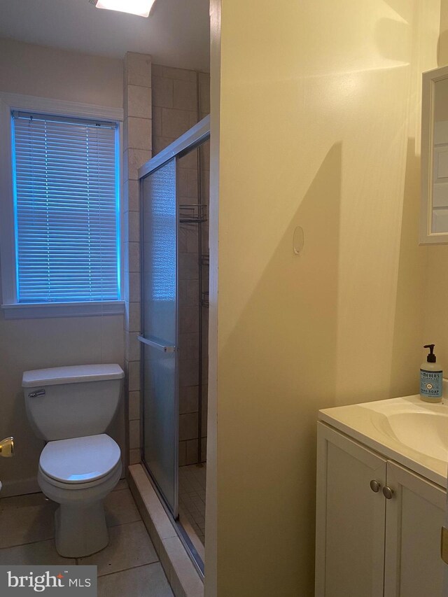 full bathroom with tile patterned flooring, a shower stall, toilet, and vanity