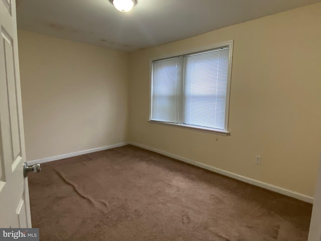 carpeted empty room featuring baseboards