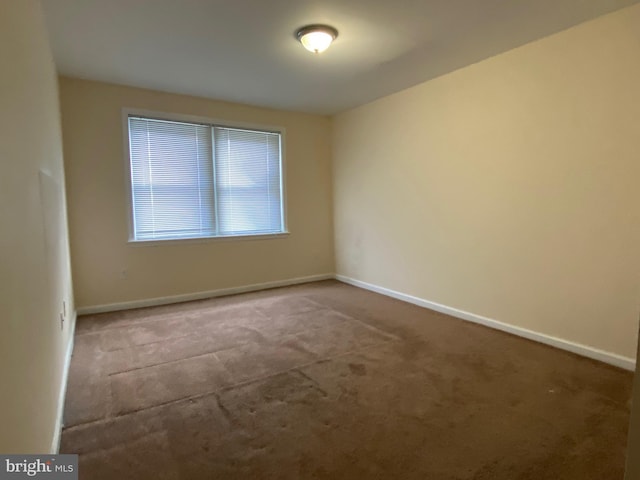 carpeted empty room featuring baseboards