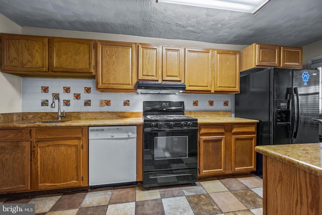 kitchen featuring under cabinet range hood, tasteful backsplash, black appliances, and a sink