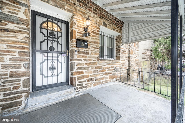 entrance to property featuring stone siding and fence