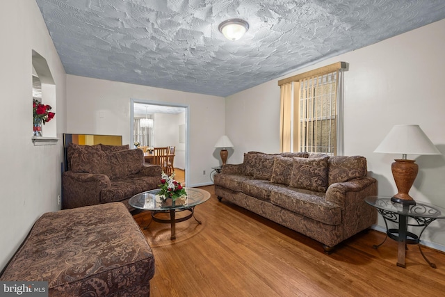 living room featuring baseboards, a textured ceiling, and wood finished floors