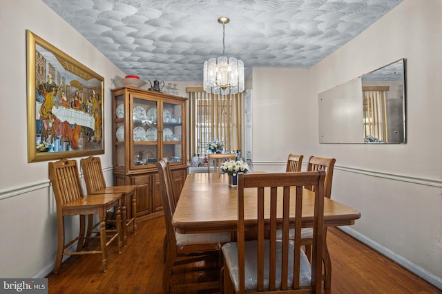 dining space with baseboards, wood-type flooring, and a chandelier