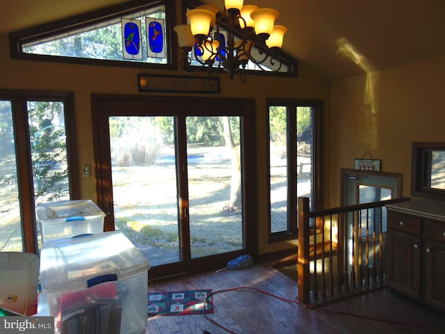 doorway to outside featuring lofted ceiling, an inviting chandelier, and wood finished floors