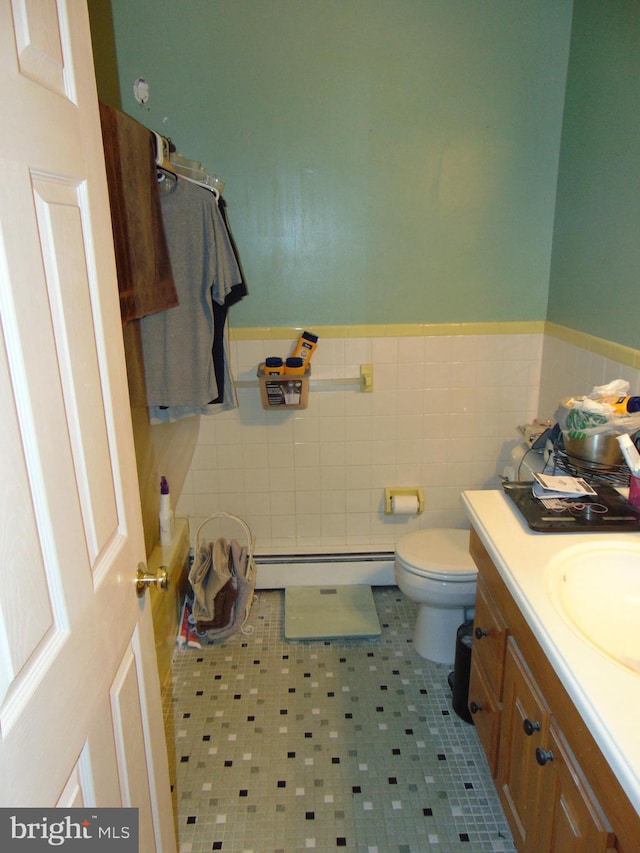 bathroom featuring a wainscoted wall, toilet, vanity, tile walls, and a baseboard radiator