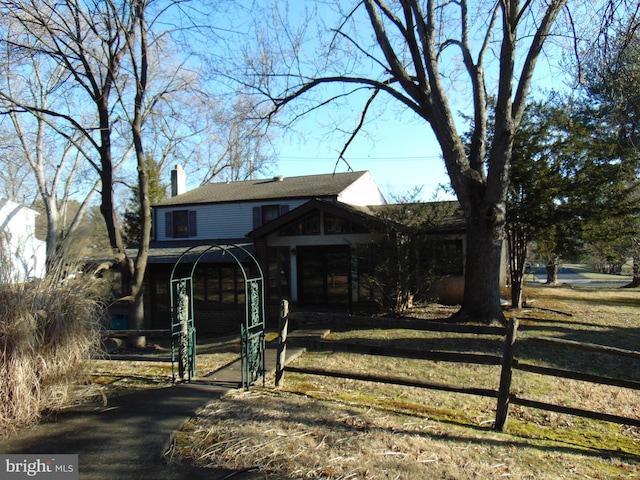 view of front of property featuring a fenced front yard, aphalt driveway, a chimney, and a gate