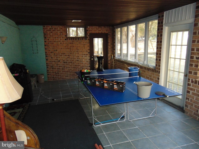 rec room featuring brick wall, wooden ceiling, and tile patterned flooring