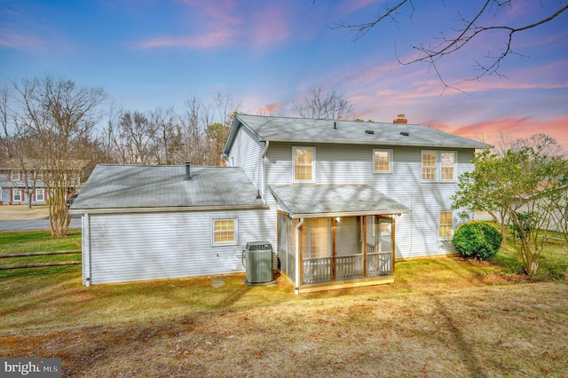 back of house featuring cooling unit, a chimney, a yard, and a sunroom