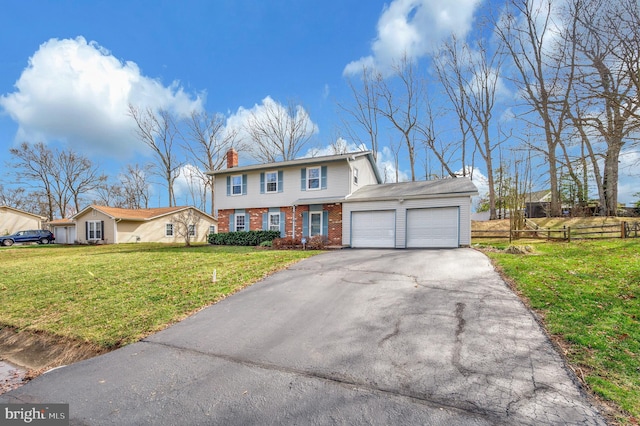 colonial house with brick siding, a front lawn, a chimney, a garage, and driveway