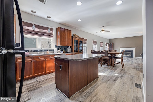 kitchen featuring light wood-style flooring, ceiling fan, a center island, and freestanding refrigerator