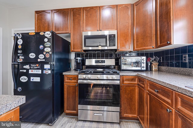 kitchen with decorative backsplash, light wood-style flooring, a toaster, and appliances with stainless steel finishes