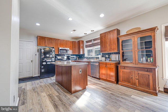 kitchen featuring visible vents, light wood finished floors, stainless steel appliances, decorative backsplash, and a center island