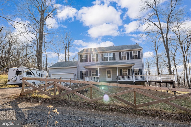 colonial-style house with covered porch, an attached garage, and fence