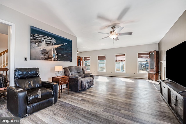 living area featuring stairway, wood finished floors, baseboards, and ceiling fan