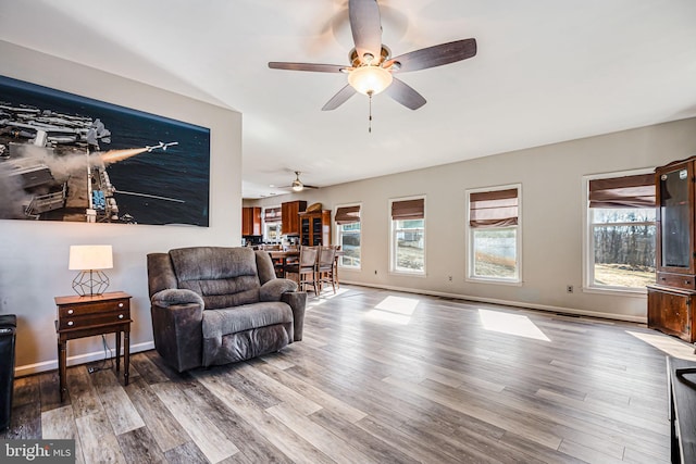 living room featuring baseboards, wood finished floors, and a ceiling fan