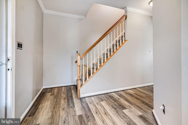 stairway featuring crown molding, wood finished floors, and baseboards