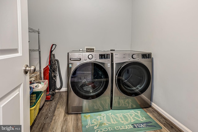 laundry area with laundry area, washer and dryer, baseboards, and wood finished floors