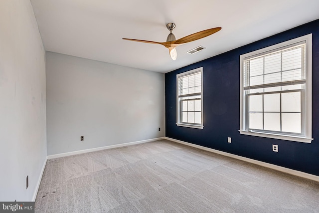 empty room with carpet, a ceiling fan, visible vents, and baseboards