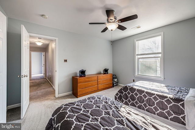 carpeted bedroom with visible vents, baseboards, and a ceiling fan