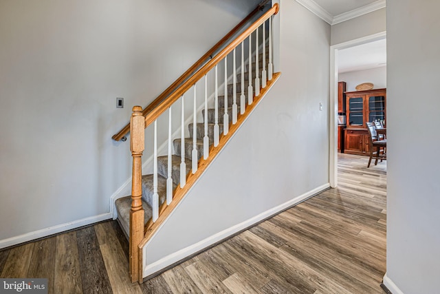 staircase with baseboards, wood finished floors, and ornamental molding