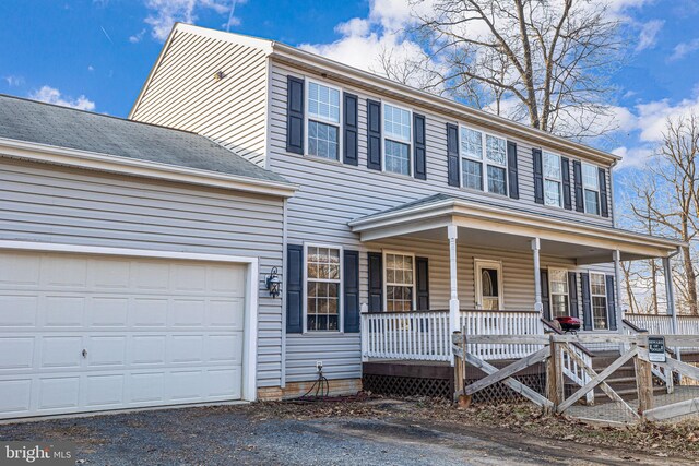 colonial house with aphalt driveway, covered porch, and an attached garage