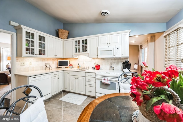 kitchen featuring white appliances, visible vents, vaulted ceiling, white cabinetry, and tasteful backsplash