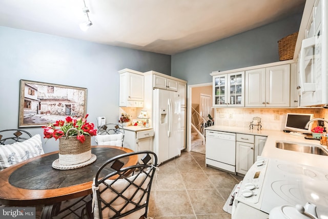 kitchen with backsplash, light countertops, light tile patterned floors, white appliances, and a sink