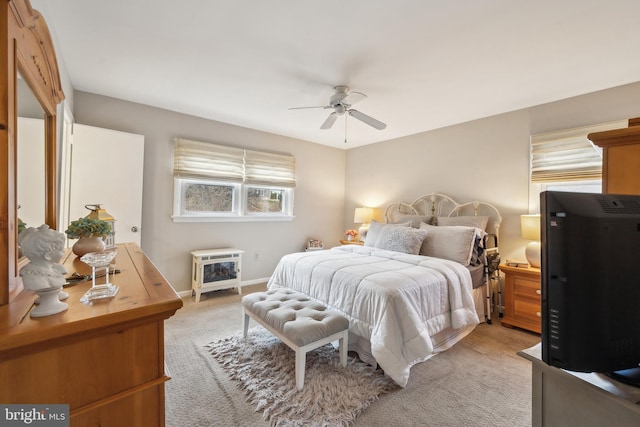 bedroom with a ceiling fan, baseboards, and light carpet