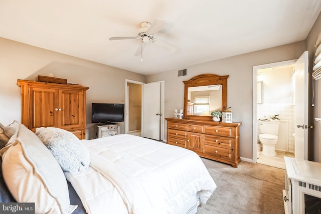 bedroom with visible vents, light colored carpet, ensuite bathroom, and ceiling fan