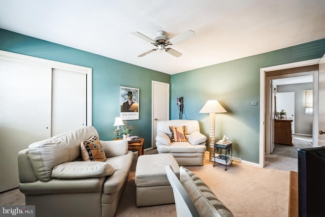 carpeted living area with baseboards and ceiling fan