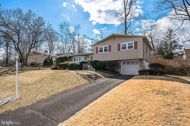 tri-level home featuring aphalt driveway, a garage, a front yard, and stone siding