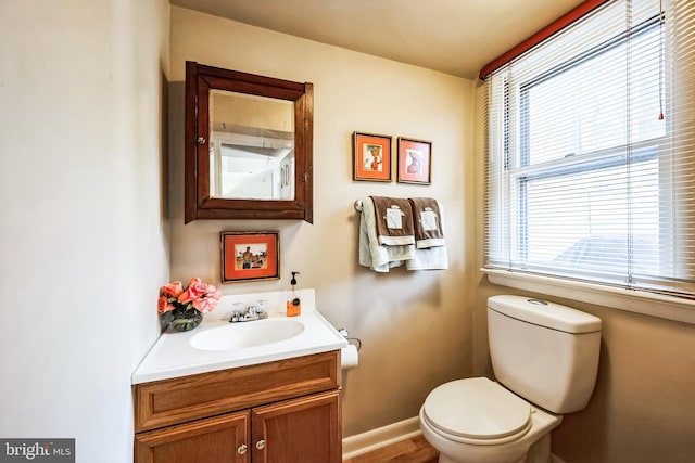 half bath with vanity, toilet, and baseboards