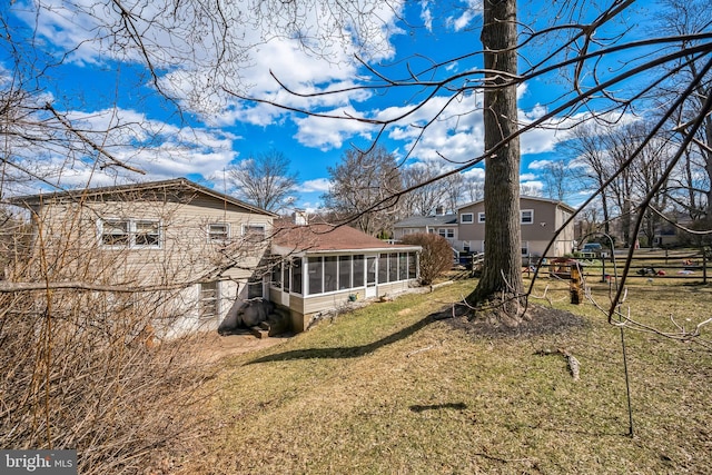 rear view of property featuring a lawn, a chimney, fence, and a sunroom