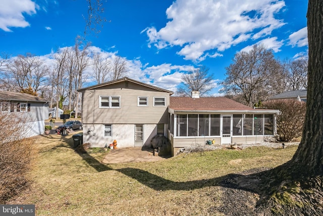 rear view of property with a patio area, a lawn, a chimney, and a sunroom