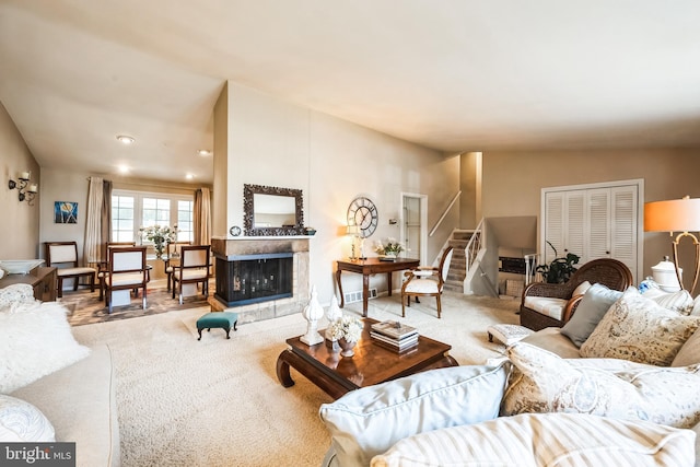 carpeted living room featuring stairway, a multi sided fireplace, and vaulted ceiling