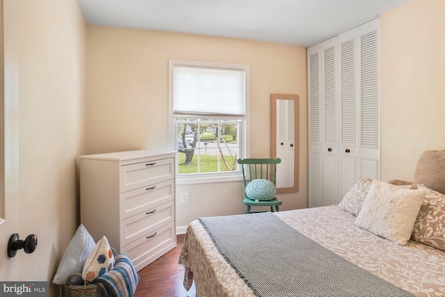 bedroom with dark wood-type flooring, a closet, and baseboards