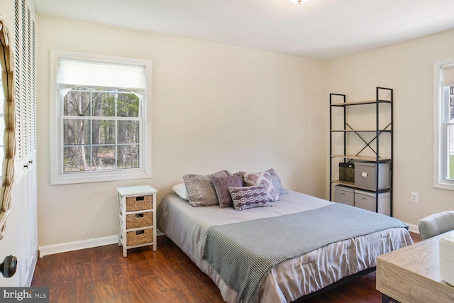 bedroom with baseboards, multiple windows, and dark wood-style floors