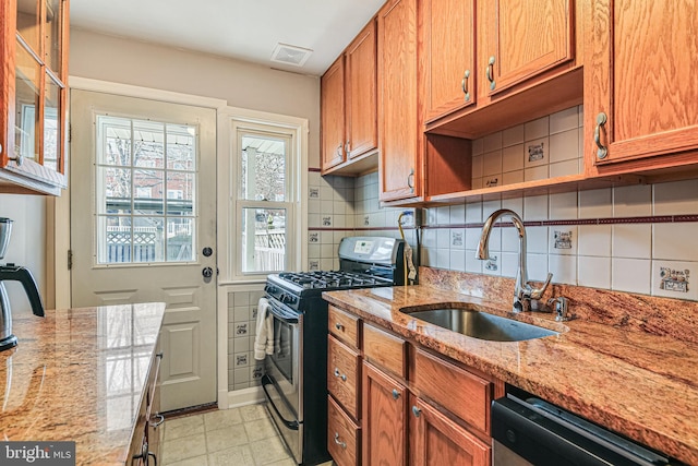 kitchen with visible vents, light stone countertops, decorative backsplash, stainless steel appliances, and a sink