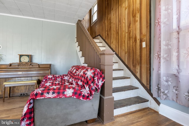 staircase featuring wooden walls, ornamental molding, and hardwood / wood-style flooring