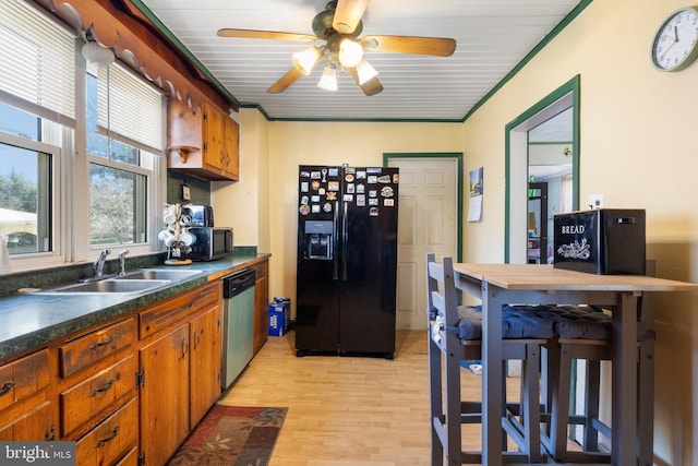 kitchen with light wood finished floors, a sink, stainless steel dishwasher, dark countertops, and black refrigerator with ice dispenser