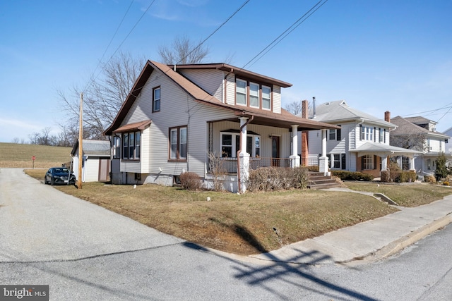 view of front of house with a porch, an outbuilding, and a front yard