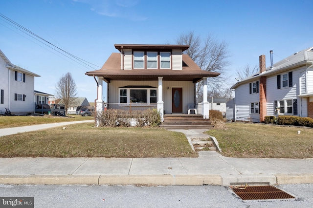 view of front of property with a porch, a front yard, and board and batten siding