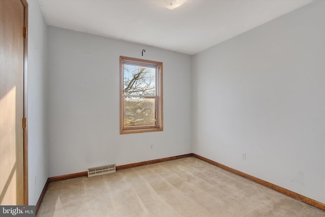 empty room with visible vents, light carpet, and baseboards