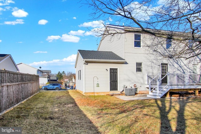 rear view of house featuring central AC unit, fence, a yard, a shingled roof, and a deck