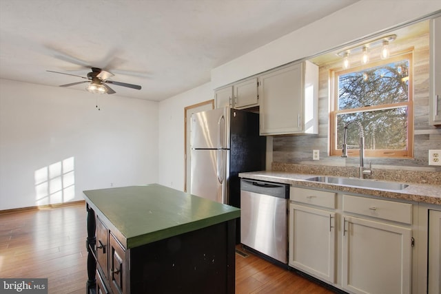 kitchen featuring backsplash, appliances with stainless steel finishes, wood finished floors, and a sink